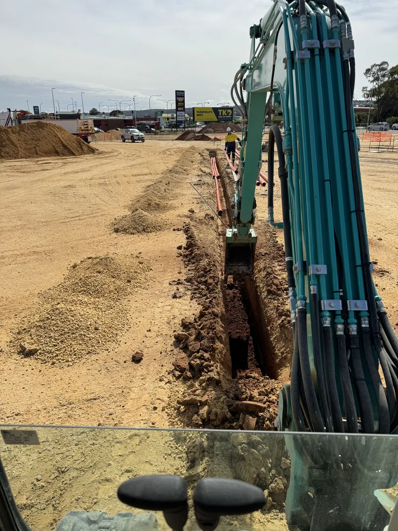 Excavator digging trench at construction site.
