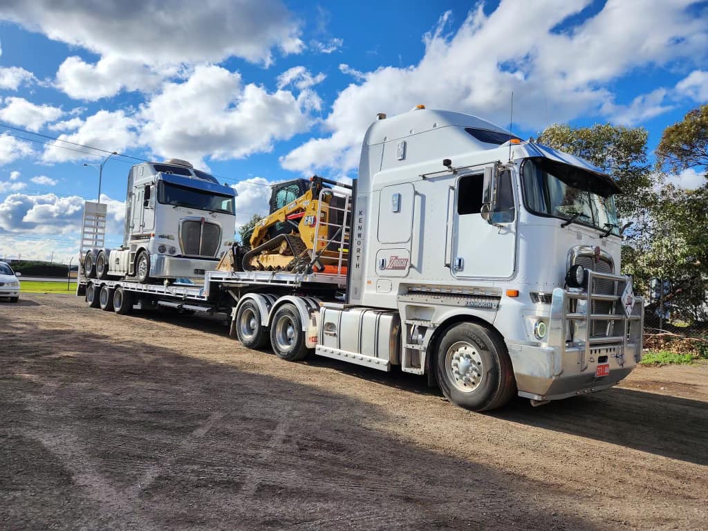 Truck hauling construction equipment on trailer.